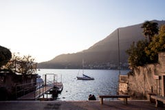 Porto pequeno no por do sol no lago Como com um barco de visita Sulo imagens de stock Porto pequeno no por do sol no lago Como com um barco de visita Sulo imagens de stock