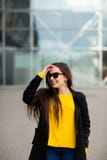 Portr?t einer sch?nen modernen stilvollen Frau in der hellen gelben Strickjacke Stra?enartschie?en stockfotografie Portr?t einer sch?nen modernen stilvollen Frau in der hellen gelben Strickjacke Stra?enartschie?en stockfotografie