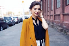 Portr?tmodefrau, die auf Stra?e geht Sie tr?gt die gelbe Jacke und l?chelt, um mit Seiten zu versehen lizenzfreie stockfotografie Portr?tmodefrau, die auf Stra?e geht Sie tr?gt die gelbe Jacke und l?chelt, um mit Seiten zu versehen lizenzfreie stockfotografie