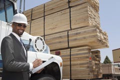 Portrait of African American male contractor writing notes while standing by logging truck royalty free stock images Portrait of African American male contractor writing notes while standing by logging truck royalty free stock images