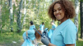 Portrait of Afro-American volunteer busy with paperwork in polluted forest
