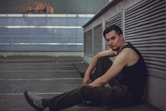 Portrait of attractive dark-haired young man with funny face expression sitting against an urban background royalty free stock photos Portrait of attractive dark-haired young man with funny face expression sitting against an urban background royalty free stock photos