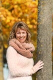 Happy mature woman leaning against a tree in front of autumn lea stock photos Happy mature woman leaning against a tree in front of autumn lea stock photos