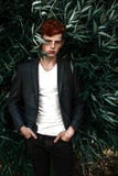 Portrait of attractive stylish young guy model with red hair and freckles sitting on green grass, wearing jacket. Fashionable outd royalty free stock image Portrait of attractive stylish young guy model with red hair and freckles sitting on green grass, wearing jacket. Fashionable outd royalty free stock image