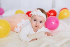 Portrait of a baby with brown eyes. The girl in the armband and dress is lying on the bed and wants to crawl, the child royalty free stock photography Portrait of a baby with brown eyes. The girl in the armband and dress is lying on the bed and wants to crawl, the child royalty free stock photography