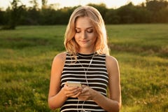 A portrait of beautiful girl standing on green background wearing striped dress holding her mobile phone. An attentive look into stock photo A portrait of beautiful girl standing on green background wearing striped dress holding her mobile phone. An attentive look into stock photo