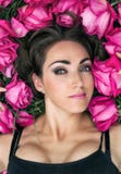 Portrait of a beautiful young woman, she is lying on the grass surrounded by roses. Festive background. stock photography Portrait of a beautiful young woman, she is lying on the grass surrounded by roses. Festive background. stock photography