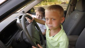 Portrait of a boy in a car in the front seat with a lollipop.