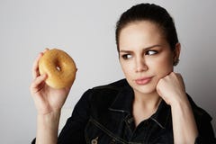 Portrait of a confused beatiful caucasian woman thinking to eat donut or not isolated over white background. stock image Portrait of a confused beatiful caucasian woman thinking to eat donut or not isolated over white background. stock image