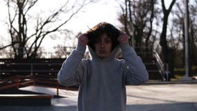 Portrait d'un jeune homme beau avec les cheveux boucl?s fonc?s Garçon de l'adolescence dans le hoodie gris marchant au-dessus du clips vidéos Portrait d'un jeune homme beau avec les cheveux boucl?s fonc?s Garçon de l'adolescence dans le hoodie gris marchant au-dessus du clips vidéos