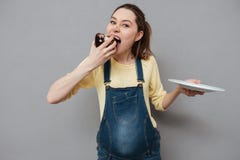 Portrait d'une femme assez enceinte affamée mangeant le gâteau de chocolat photos libres de droits Portrait d'une femme assez enceinte affamée mangeant le gâteau de chocolat photos libres de droits