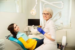 Portrait d'une femme de sourire, se reposant à la chaise dentaire avec le docteur au bureau dentaire images stock Portrait d'une femme de sourire, se reposant à la chaise dentaire avec le docteur au bureau dentaire images stock