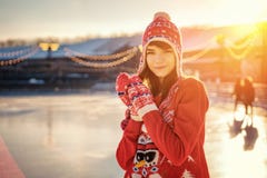 Portrait d'une jeune femme dans un chapeau sur la patinoire, un sourire sur son visage, le soleil photographie stock libre de droits Portrait d'une jeune femme dans un chapeau sur la patinoire, un sourire sur son visage, le soleil photographie stock libre de droits