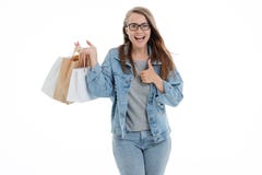 Portrait d'une jeune fille de sourire habillée dans des jeans bleus de denim tenant des sacs à provisions et regardant la caméra photo stock Portrait d'une jeune fille de sourire habillée dans des jeans bleus de denim tenant des sacs à provisions et regardant la caméra photo stock