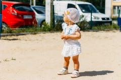 Portrait d'une petite fille dans une robe blanche et un chapeau blanc avec des fleurs sur le fond des voitures, sur le terrain de photo libre de droits Portrait d'une petite fille dans une robe blanche et un chapeau blanc avec des fleurs sur le fond des voitures, sur le terrain de photo libre de droits