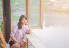 Portrait de belle femme asiatique se reposer sur la chaise en bois table pr?s de la fen?tre photo stock Portrait de belle femme asiatique se reposer sur la chaise en bois table pr?s de la fen?tre photo stock