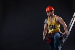 Portrait de constructeur beau avec l'échelle de construction sur le fond noir photo libre de droits Portrait de constructeur beau avec l'échelle de construction sur le fond noir photo libre de droits