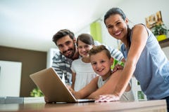 Portrait de famille heureuse utilisant l'ordinateur portable dans le salon images stock Portrait de famille heureuse utilisant l'ordinateur portable dans le salon images stock