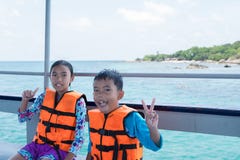 Portrait de garçon et de fille asiatiques sur le bateau à la plage photos stock Portrait de garçon et de fille asiatiques sur le bateau à la plage photos stock