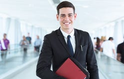 Portrait de jeune homme d'affaires heureux devant le fond moderne occupé photographie stock Portrait de jeune homme d'affaires heureux devant le fond moderne occupé photographie stock