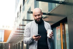 Portrait de jeune homme de sourire utilisant le smartphone sur la rue de ville L'homme envoie le message textuel lifestyle R?seau photos stock Portrait de jeune homme de sourire utilisant le smartphone sur la rue de ville L'homme envoie le message textuel lifestyle R?seau photos stock