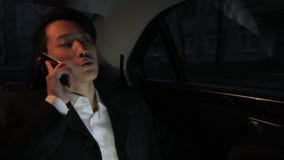 Portrait de l'homme d'affaires coréen qui parle sur le smartphone dans le taxi confortable foncé banque de vidéos Portrait de l'homme d'affaires coréen qui parle sur le smartphone dans le taxi confortable foncé banque de vidéos
