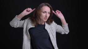 Portrait de la femme caucasienne de brune d'une cinquantaine d'années dansant modestement sur le fond noir banque de vidéos Portrait de la femme caucasienne de brune d'une cinquantaine d'années dansant modestement sur le fond noir banque de vidéos