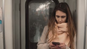 Portrait de la jeune belle femme se tenant dans le souterrain La fille utilise le smartphone, passent en revue l'Internet dans le photographie stock libre de droits Portrait de la jeune belle femme se tenant dans le souterrain La fille utilise le smartphone, passent en revue l'Internet dans le photographie stock libre de droits