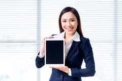 Portrait de sourire de femme d'affaires dans la fenêtre se tenante prêt de bureau montrant l'écran du comprimé numérique Image stock Portrait de sourire de femme d'affaires dans la fenêtre se tenante prêt de bureau montrant l'écran du comprimé numérique Image stock