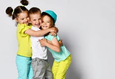 Portrait de studio des enfants sur un fond clair : plein tir de corps de trois enfants dans les vêtements lumineux, deux filles e image stock Portrait de studio des enfants sur un fond clair : plein tir de corps de trois enfants dans les vêtements lumineux, deux filles e image stock