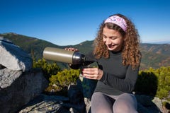 Portrait de thé se renversant de jeune femme heureuse hors de thermos image stock Portrait de thé se renversant de jeune femme heureuse hors de thermos image stock