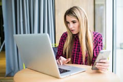 Portrait de vue de côté de jeune recherche de femme d'affaires dans l'ordinateur portable pour écrire un message au téléphone dan Image libre de droits Portrait de vue de côté de jeune recherche de femme d'affaires dans l'ordinateur portable pour écrire un message au téléphone dan Image libre de droits