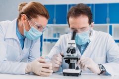 portrait des chercheurs dans les masques médicaux et des gants fonctionnant avec le microscope ensemble photo stock portrait des chercheurs dans les masques médicaux et des gants fonctionnant avec le microscope ensemble photo stock