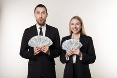 Portrait des couples dans les costumes noirs choqués tenant des billets de banque d'argent dans des mains photos libres de droits Portrait des couples dans les costumes noirs choqués tenant des billets de banque d'argent dans des mains photos libres de droits