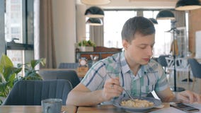 Portrait des pâtes d'eateng de jeune homme et du smartphone d'utilisation en café banque de vidéos Portrait des pâtes d'eateng de jeune homme et du smartphone d'utilisation en café banque de vidéos