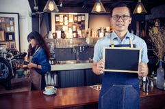 Portrait du barman asiatique de sourire tenant le menu vide de tableau photographie stock libre de droits Portrait du barman asiatique de sourire tenant le menu vide de tableau photographie stock libre de droits