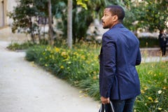 Portrait du jeune homme d'affaires afro-américain sûr heureux dans le tenue de soirée marchant au parc de ville avec le sac de vo photographie stock libre de droits Portrait du jeune homme d'affaires afro-américain sûr heureux dans le tenue de soirée marchant au parc de ville avec le sac de vo photographie stock libre de droits