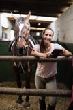 Portrait du jockey féminin de sourire à l'aide du comprimé numérique en se tenant prêt le cheval photo libre de droits Portrait du jockey féminin de sourire à l'aide du comprimé numérique en se tenant prêt le cheval photo libre de droits