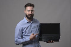 Portrait déprimé du jeune homme adulte heureux de sourire d'affaires tenant l'ordinateur portable et pointage et l'écran d'ordina images libres de droits Portrait déprimé du jeune homme adulte heureux de sourire d'affaires tenant l'ordinateur portable et pointage et l'écran d'ordina images libres de droits