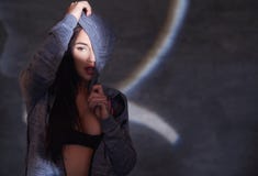 Portrait en gros plan d'une fille séduisante de brune dans un hoodie posant dans le studio photos stock Portrait en gros plan d'une fille séduisante de brune dans un hoodie posant dans le studio photos stock