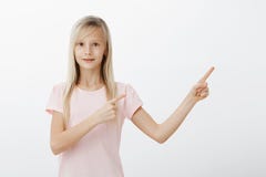 Portrait of excited surprised adorable little girl with blond hair, pointing at upper right corner and staring at camera royalty free stock photos Portrait of excited surprised adorable little girl with blond hair, pointing at upper right corner and staring at camera royalty free stock photos