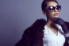 Portrait of glam dark-haired model in stylish classic sunglasses wearing white blouse, sable coat and set of luxurious jewelry royalty free stock photos Portrait of glam dark-haired model in stylish classic sunglasses wearing white blouse, sable coat and set of luxurious jewelry royalty free stock photos
