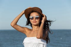 Portrait of gorgeous dark-haired girl in white dress, sunglasses and hat near the sea on a sunny day. royalty free stock photos Portrait of gorgeous dark-haired girl in white dress, sunglasses and hat near the sea on a sunny day. royalty free stock photos