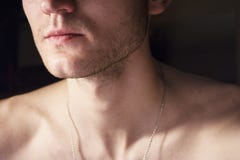 Portrait of a handsome guy with a naked torso. Photo of a close-up in a dark room and light from a lamp. Soft light. Green-eyed br Stock Photo Portrait of a handsome guy with a naked torso. Photo of a close-up in a dark room and light from a lamp. Soft light. Green-eyed br Stock Photo