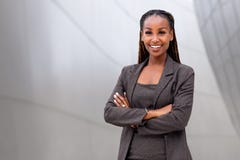 Portrait of a happy African American female company leader, CEO, boss, executive, standing in front of company building, copy spac