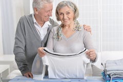 Portrait of happy senior couple during ironing at home stock photos Portrait of happy senior couple during ironing at home stock photos