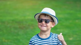 Portrait happy smiling little boy in sunglasses and hat having fun dancing in summer park stock video Portrait happy smiling little boy in sunglasses and hat having fun dancing in summer park stock video