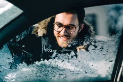 Portrait haut étroit de l'homme utilisant le grattoir pour nettoyer des fenêtres de voiture Transport d'hiver et concept de véhic photos stock Portrait haut étroit de l'homme utilisant le grattoir pour nettoyer des fenêtres de voiture Transport d'hiver et concept de véhic photos stock