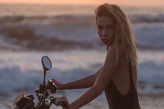 Portrait haut étroit de modèle blond dans le maillot de bain noir se reposant sur la moto, image stock Portrait haut étroit de modèle blond dans le maillot de bain noir se reposant sur la moto, image stock