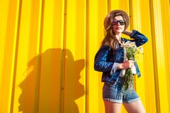 Portrait of hipster girl wearing glasses and hat with flowers against yellow background. Summer outfit. Fashion. Space royalty free stock images Portrait of hipster girl wearing glasses and hat with flowers against yellow background. Summer outfit. Fashion. Space royalty free stock images